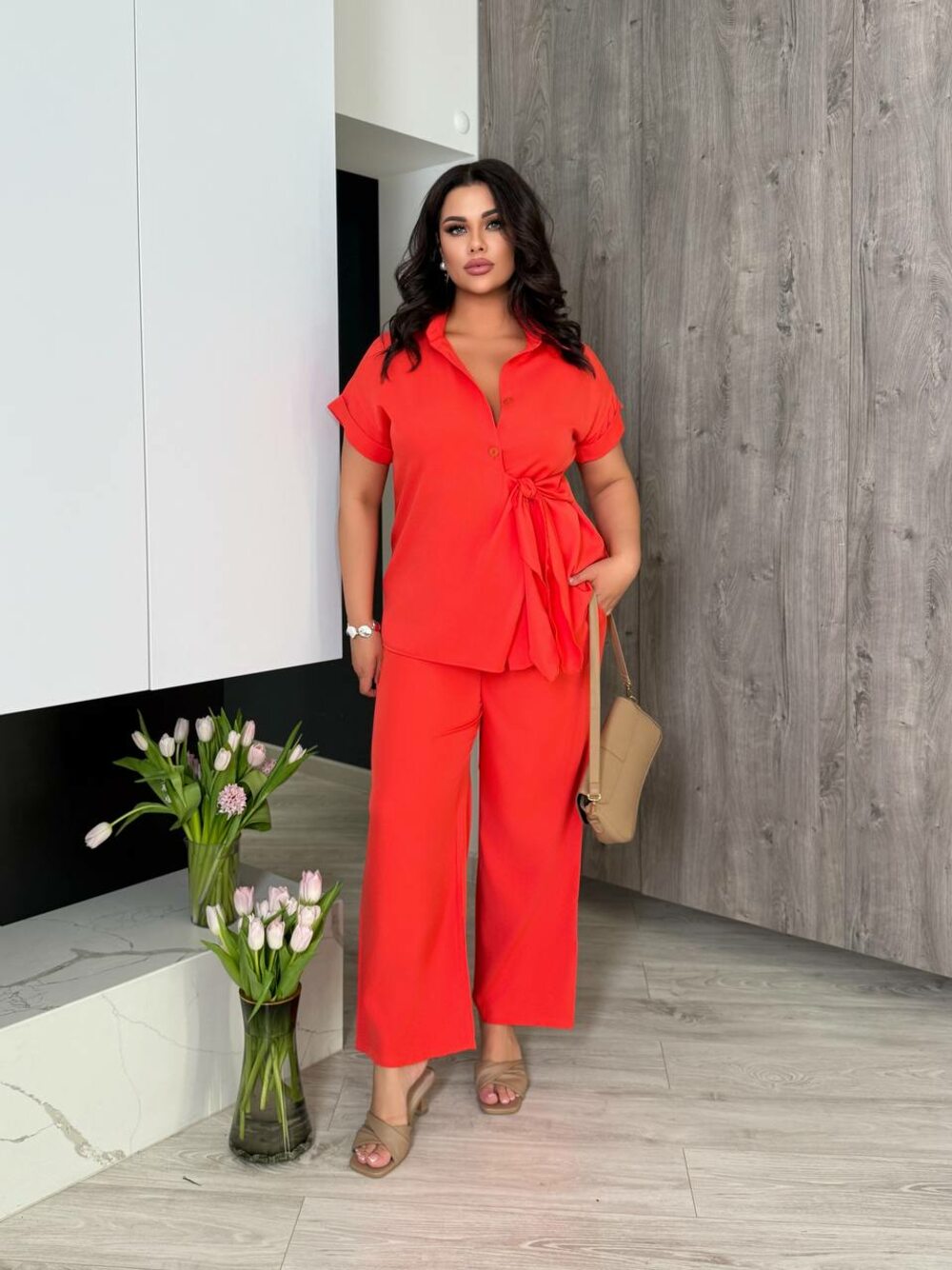Костюм складається з брюк та блузи оригінального крою, колір кораловий.