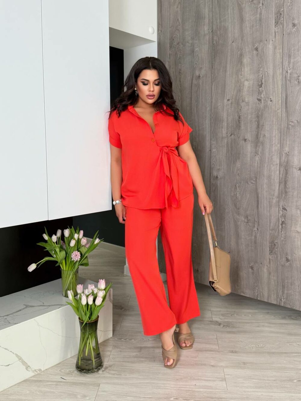 Костюм складається з брюк та блузи оригінального крою, колір кораловий.